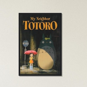 Pode incluir: Um poster emoldurado do filme de anima&ccedil;&atilde;o "Meu Vizinho Totoro". A imagem mostra uma menina com um guarda-chuva vermelho em um ponto de &ocirc;nibus, junto com uma criatura grande e peluda. O t&iacute;tulo "TOTORO" est&aacute; em letras laranja.