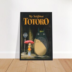 Pode incluir: Um poster emoldurado do filme de anima&ccedil;&atilde;o "Meu Vizinho Totoro". A obra de arte retrata uma menina com um guarda-chuva vermelho, em p&eacute; perto de um ponto de &ocirc;nibus com uma criatura grande e peluda. O t&iacute;tulo "Totoro" est&aacute; em letras grandes e laranja.