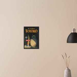 Pode incluir: Impress&atilde;o emoldurada de "Meu Vizinho Totoro" com texto dourado. A imagem mostra um grande personagem Totoro cinza e uma menina com um guarda-chuva vermelho. Um ponto de &ocirc;nibus &eacute; vis&iacute;vel ao fundo.