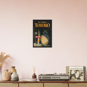 Pode incluir: Impress&atilde;o emoldurada com o t&iacute;tulo "My Neighbor Totoro" em letras douradas. A obra de arte retrata uma jovem com um guarda-chuva e um grande esp&iacute;rito da floresta. O fundo &eacute; uma cena escura e atmosf&eacute;rica.
