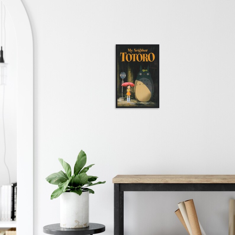 Pode incluir: Uma impress&atilde;o emoldurada do filme de anima&ccedil;&atilde;o "Meu Vizinho Totoro". A obra de arte retrata uma jovem com um guarda-chuva vermelho, ao lado de uma grande criatura peluda. O t&iacute;tulo "My Neighbor Totoro" est&aacute; em laranja.