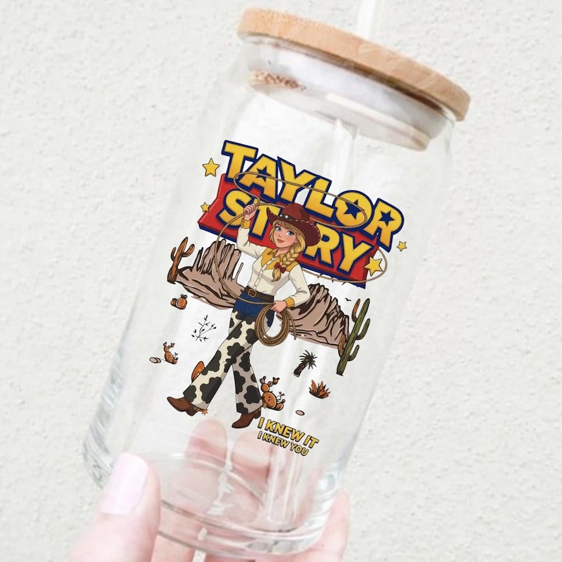 May include: A clear glass tumbler with a bamboo lid featuring a graphic of a cowgirl holding a lasso, desert cacti, and the text Taylor Story and I Knew It I Knew You. The design includes a yellow and red logo style font and cow print pants.
