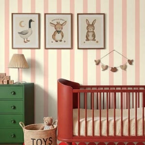 Op de afbeelding: Een kinderkamer met een rood ledikant, een groene commode en een rieten mand met het opschrift "TOYS". De muren zijn gestreept, met ingelijste dierenillustraties. Een teddybeer zit in de mand. De vloer heeft een rood-wit geblokt patroon.
