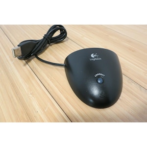 May include: A black Logitech receiver with a USB cable. The receiver has a button labeled "CONNECT" and the Logitech logo. The device is on a wooden surface.