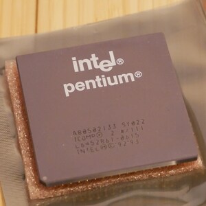 May include: A square, lavender-colored Intel Pentium processor. The Intel logo and "pentium" are printed in white. Additional text and numbers are printed below. The processor is packaged in a clear plastic sleeve.