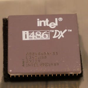 May include: A close-up of a vintage Intel i486 DX processor. The processor has a rectangular shape with a brown top and gold pins. The Intel logo and "i486 DX" are printed on the top. The text "©1989" is also visible.
