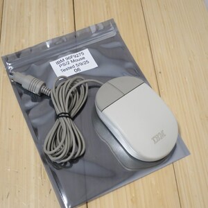 May include: A beige and grey IBM PS/2 computer mouse with a coiled cable and connector. The mouse is inside a clear plastic bag with a white label that reads: IBM 96F9275, PS/2 Mouse, Tested 5/9/25, 06. The device features two buttons.