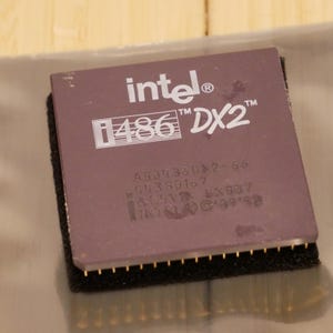 May include: A close-up of a vintage Intel i486 DX2 processor. The processor is a rectangular shape with a dark purple top and gold pins. The Intel logo and model information are printed in white.