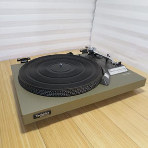 May include: A Technics by Panasonic turntable with a matte olive green base, a circular black grooved platter, and a silver tone arm. The control panel features the text Frequency Generator Servo and SL-20, with a Technics logo on the front left.