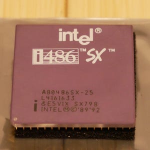 May include: A close-up of a purple Intel i486 SX processor. The processor has white text that reads "intel", "i486 SX", and other model information. The bottom edge has gold pins and a black base.