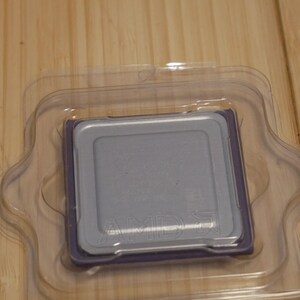 May include: A silver AMD processor in a clear plastic clamshell package. The processor has a rectangular shape with a silver top and a purple border. The AMD logo is visible on the processor.