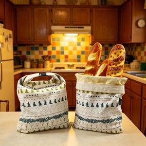May include: Two off-white fabric bags featuring a repeating pattern of green pine trees, dotted lines, and small trees. One bag is closed with a black plastic buckle, while the other is open and filled with three long, golden-brown crusty loaves of bread.