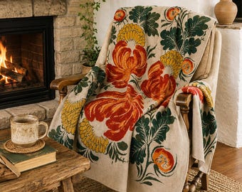 Peut inclure: Un plaid beige drapé sur un fauteuil en bois, orné d'un motif répétitif de grandes fleurs orange, de fleurs jaunes ressemblant à des chrysanthèmes et de feuillage vert foncé. Le textile présente une texture tissée et recouvre le siège.