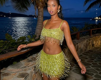 Conjunto de dos piezas con lentejuelas y flecos, top corto brillante y minifalda, ideal para fiestas y festivales.