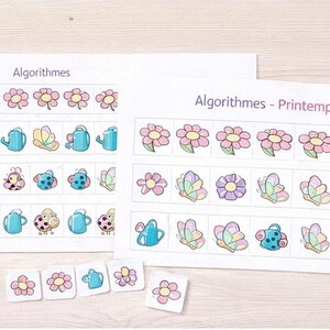 Peut inclure: Deux feuilles de papier blanc avec le mot "Algorithmes" imprim&eacute;, pr&eacute;sentant des rang&eacute;es d'illustrations color&eacute;es de fleurs, d'arrosoirs, de papillons et de coccinelles. De petits carreaux assortis sont &eacute;parpill&eacute;s en dessous.