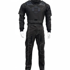 Puede incluir: Traje táctico negro con costuras blancas, exhibido en un maniquí. El traje incluye una parte superior de cuello alto con paneles reforzados en los hombros y el pecho, y pantalones a juego. El diseño presenta múltiples paneles y áreas reforzadas.