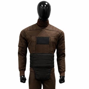 Könnte beinhalten: Brauner Overall mit hohem Kragen, schwarzen Akzenten und Knieschonern. Das Kostüm wird auf einer Schaufensterpuppe mit schwarzem Kopf und Händen präsentiert. Das Outfit beinhaltet einen breiten schwarzen Gürtel und ist für ein futuristisches Thema.