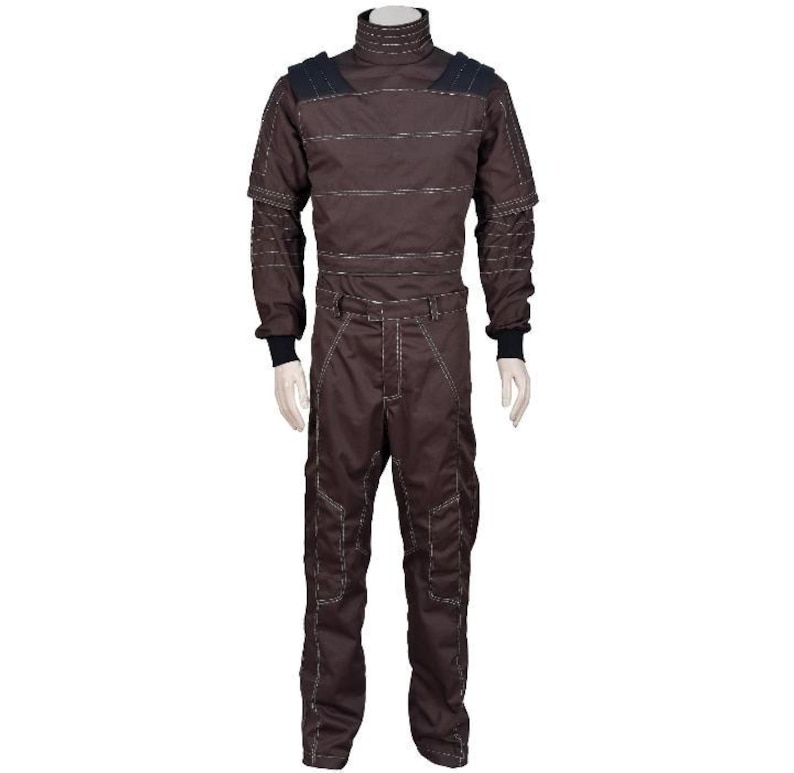 May include: A dark brown long-sleeved jumpsuit featuring a high mock neck collar, structured shoulder panels, and black ribbed cuffs. The garment is detailed with horizontal stitching across the chest and vertical seams along the legs.