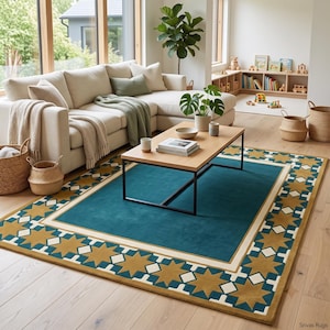 May include: A rectangular area rug featuring a solid teal center bordered by a wide frame of repeating gold star shapes and white diamond accents. The rug has a clean, flat-woven appearance with a distinct geometric pattern along the outer edges.