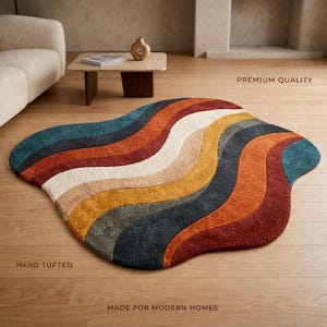 May include: An irregular, organic-shaped area rug featuring wavy, multi-colored stripes in shades of teal, dark gray, rust orange, mustard yellow, and cream. The rug is hand-tufted and includes the text PREMIUM QUALITY, HAND TUFTED, and MADE FOR MODERN HOMES.