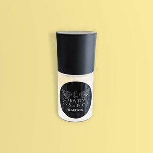 Pode incluir: Uma garrafa cilíndrica de óleo para barba com tampa preta e rótulo branco. O rótulo apresenta um design circular preto com as palavras "CREATIVE ESSENCE" e "BEARD OIL". A garrafa contém um líquido transparente.