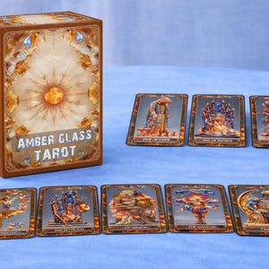 Può includere: Un mazzo di carte dei tarocchi Amber Glass con una scatola marrone con un disegno a raggiera e la scritta "Amber Glass Tarot". Vengono mostrate diverse carte dei tarocchi, ognuna con illustrazioni dettagliate nei toni del marrone, blu e oro.