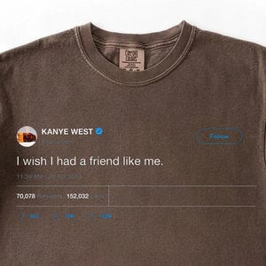 Pu&ograve; includere: T-shirt marrone con un post sui social media stampato di Kanye West. Il testo recita "I wish I had a friend like me." La maglietta ha un girocollo e maniche corte, con maniche arrotolate.