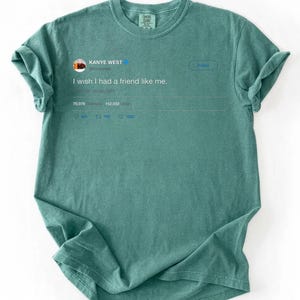 Pu&ograve; includere: Una maglietta color verde acqua con un post di Twitter stampato di Kanye West. Il post recita: "I wish I had a friend like me". La maglietta ha maniche arrotolate e girocollo.