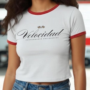 Puede incluir: Top corto blanco con ribete rojo y la palabra "Velocidad" en cursiva. El texto "Performance Engineering" está debajo de la palabra "Velocidad". Dos banderas a cuadros están encima de la palabra "Velocidad".