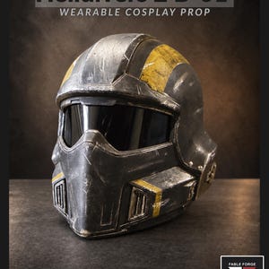 May include: A wearable cosplay helmet prop labeled Helldivers 2 B-01. The helmet features a dark gray finish with distressed yellow stripes, a black visor, and ventilation grilles on the front. The surface shows signs of wear and hand-painted details.