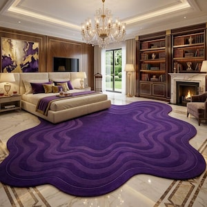 May include: A luxurious bedroom featuring a large bed with purple pillows and a matching purple blanket. A large, wavy, purple rug covers the floor. The room has a chandelier, a fireplace, and a bookshelf.