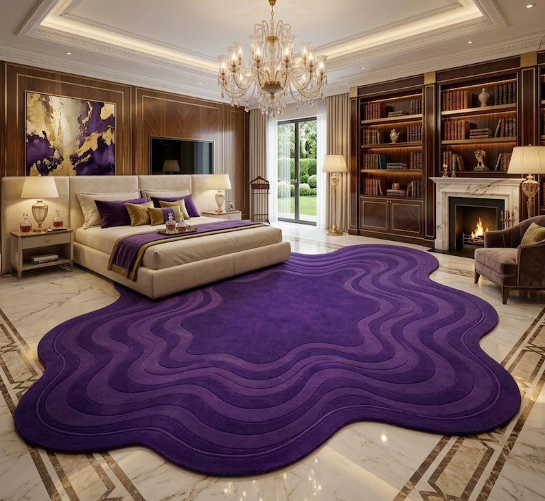 May include: A luxurious bedroom featuring a large bed with purple pillows and a matching purple blanket. A large, wavy, purple rug covers the floor. The room has a chandelier, a fireplace, and a bookshelf.