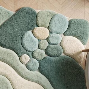 May include: A textured rug in shades of green, blue, and cream, with a design reminiscent of pebbles and flowing forms. The rug's pattern creates a natural, organic look. This decorative floor covering would suit a living room or bedroom.