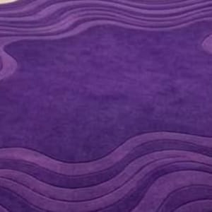 May include: A plush, purple area rug with a unique, wavy design. The rug features varying shades of purple, creating a textured, three-dimensional effect. The central area is a lighter shade, surrounded by darker, undulating borders.