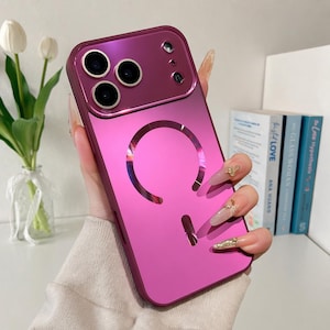 May include: A metallic magenta smartphone case featuring a glossy finish, a circular magnetic charging ring on the back, and a rectangular camera module cutout with three circular lens openings and two smaller circular sensor cutouts.