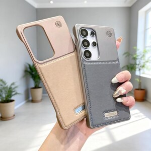 May include: Two-tone phone cases in beige and gray. The cases have a rectangular camera cutout and a speaker hole. The gray case is held by a person. The cases have a leather-like texture and a small rectangular accent.