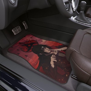 Könnte beinhalten: Auto-Fußmatte mit einer rot-schwarzen Grafik im Anime-Stil. Die Matte zeigt eine Figur mit langen schwarzen Haaren und einem roten Hintergrund mit einem kreisförmigen Design und fliegenden Vögeln. Die Matte befindet sich in einem Auto.