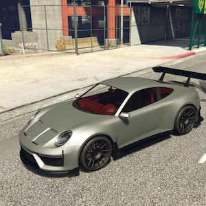 Peut inclure: Une voiture de sport argentée avec un aileron arrière noir et des roues noires est garée sur une route pavée. La voiture a un intérieur rouge et des rayures blanches sur le capot. C'est un coupé.