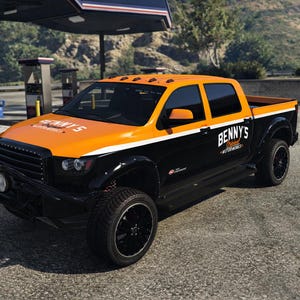 Peut inclure: Un pick-up noir et orange avec le texte "Benny's Motorworks" sur le côté. Le camion a un pare-chocs avant noir avec des lumières et des roues noires. Le camion est garé sur une surface pavée.