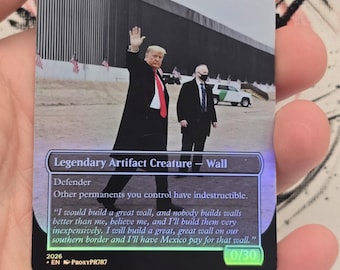 以下が含まれることがあります： 「Trump's Wall」と書かれたトレーディングカード。黒いコートを着た男性が国境の壁の近くで手を振っている画像が特徴。壁の建設に関するテキストが含まれており、ホログラフィック仕上げが施されています。