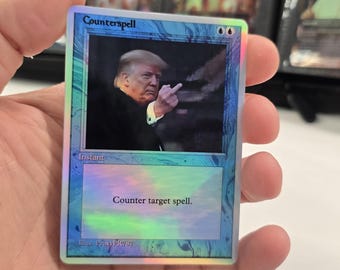 以下が含まれることがあります： 青い縁取りのホログラフィック「カウンター呪文」トレーディングカード。カードには、失礼なジェスチャーをしている人物の画像と「対象の呪文を打ち消す」というテキストが記載されています。