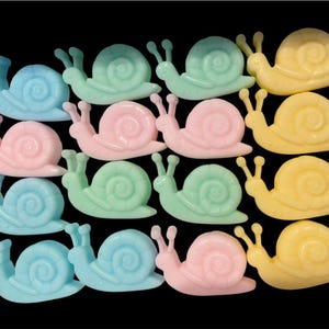 May include: A collection of colorful snail-shaped decorative items in pastel shades of blue, pink, green, and yellow. The snails have a spiral shell design and are arranged against a black background. These items could be used for crafts or home decor.