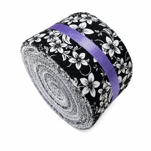 May include: A roll of fabric featuring a black background with a white floral pattern. The roll is secured with a smooth, solid purple ribbon that wraps around the center, contrasting with the monochromatic floral print of the fabric layers.