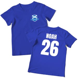 Puede incluir: Dos camisetas azules. Una camiseta tiene un peque&ntilde;o emblema con la bandera escocesa y la palabra "Scotland". La otra camiseta tiene el nombre "NOAH" y el n&uacute;mero "26" impresos en blanco en la espalda.