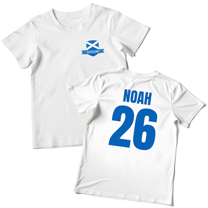 Puede incluir: Dos camisetas blancas. Una presenta un emblema escoc&eacute;s azul. La otra tiene el nombre "NOAH" y el n&uacute;mero "26" impresos en azul en la espalda. Las camisetas son probablemente para un ni&ntilde;o.