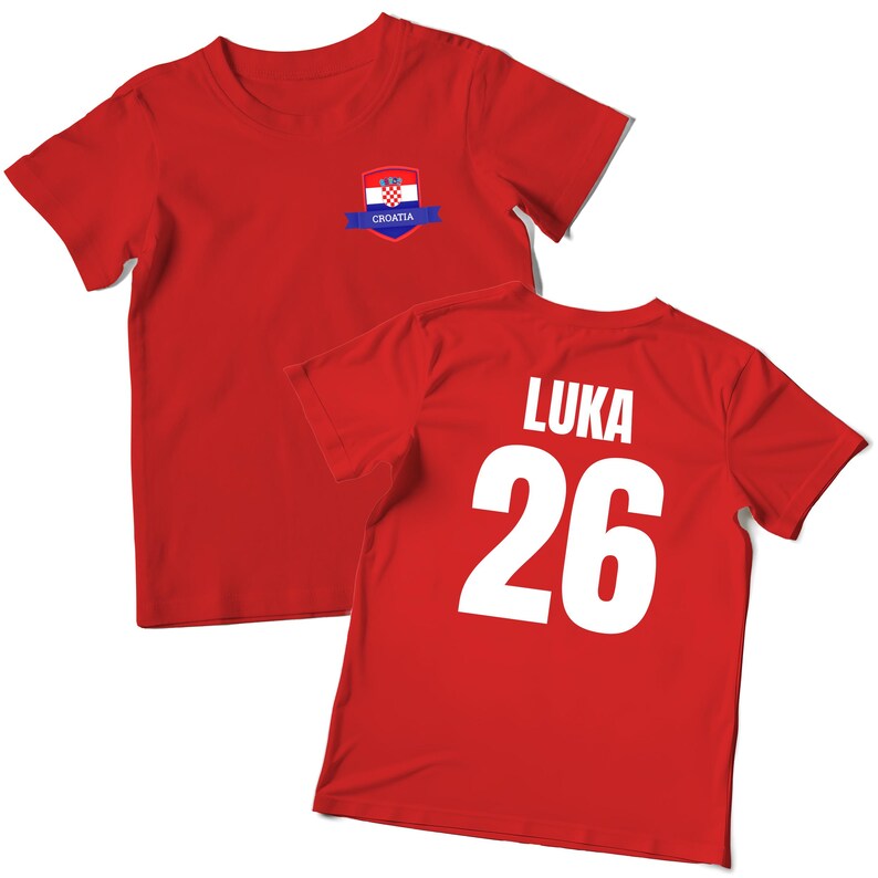 K&ouml;nnte beinhalten: Rotes T-Shirt mit dem kroatischen Flaggenemblem auf der Vorderseite und dem Namen "LUKA" und der Nummer "26" auf der R&uuml;ckseite. Das Shirt besteht aus einem weichen Material und hat kurze &Auml;rmel.