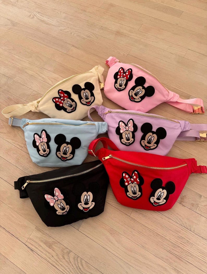 Puede incluir: Seis ri&ntilde;oneras de colores, cada una con cierre de cremallera y correa ajustable. Las ri&ntilde;oneras son de color negro, rojo, rosa, azul claro, lavanda y crema. Cada una tiene un dise&ntilde;o bordado de Mickey y Minnie Mouse.