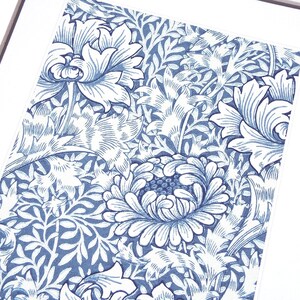 May include: A framed print featuring a detailed floral pattern in shades of blue and white. The design showcases stylized flowers and foliage, creating a classic and elegant aesthetic. The artwork is mounted on a white mat.