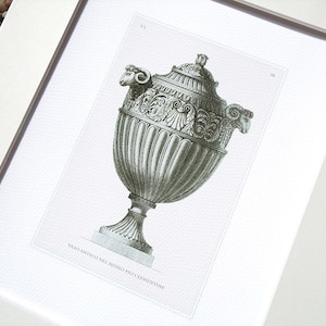 May include: A black and white illustration of a decorative urn with ram's head handles. The urn is decorated with intricate details and has a classic design. The text "Vaso antico nel museo pio Clementine" is printed below the urn.