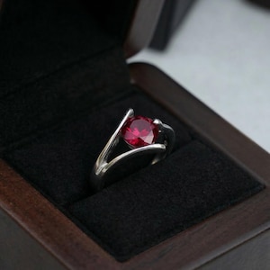 Può includere: Una tazza di ceramica bianca con un manico nero e la scritta "But first, coffee" in nero, con un carattere a mano. La tazza è su una superficie bianca.